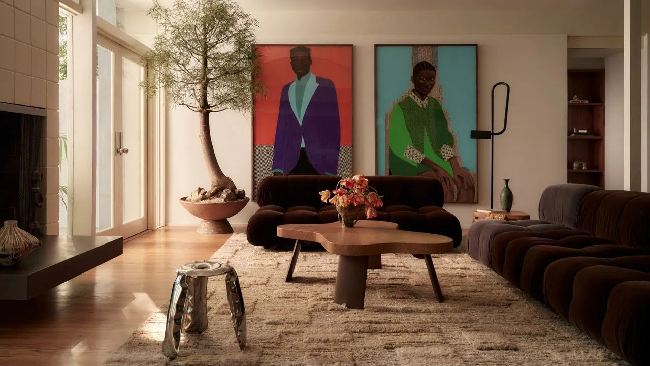 Two large colorful artworks stand above darker seating and a patterned rug.