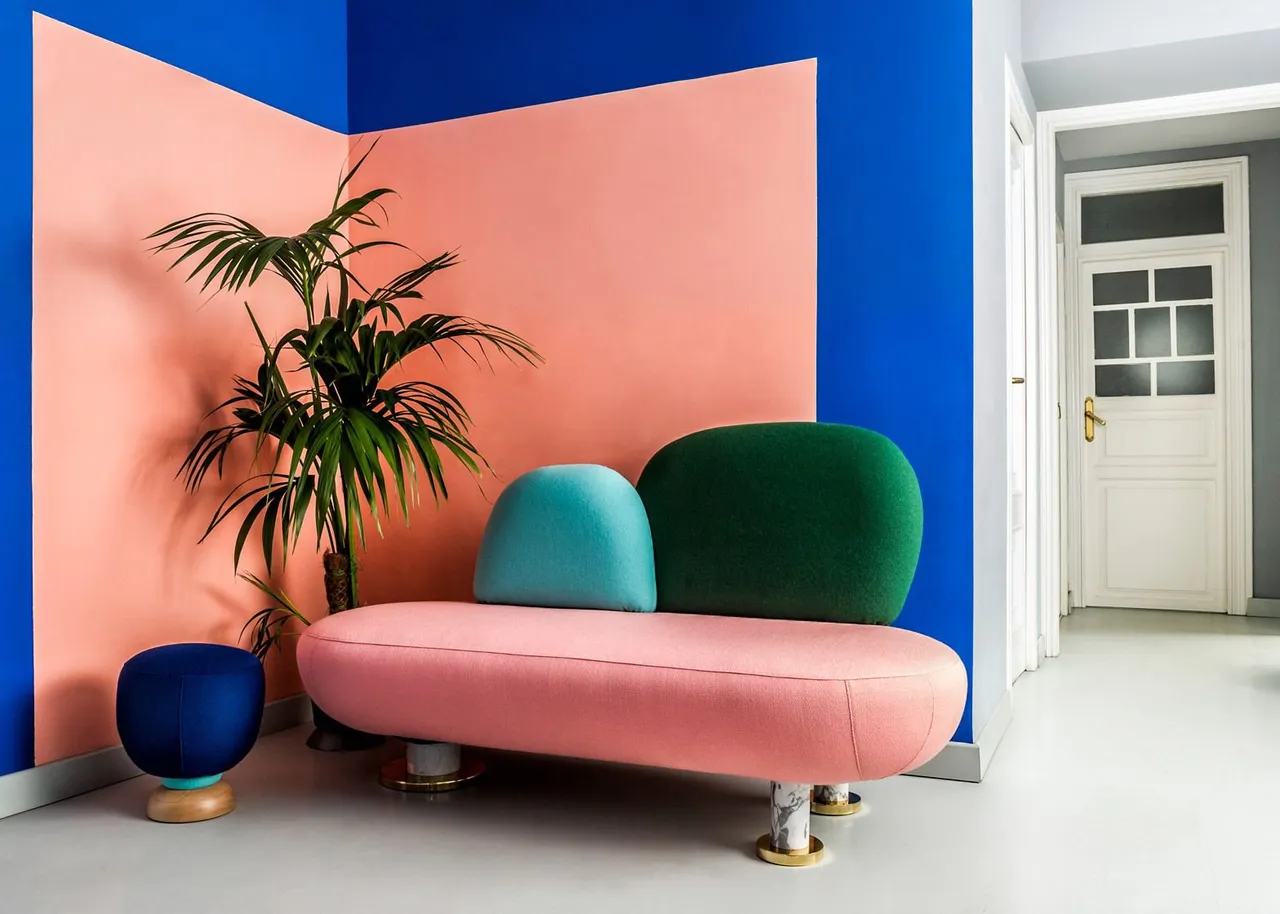 A pink sofa sits against intersecting peach and blue walls beside a plant
