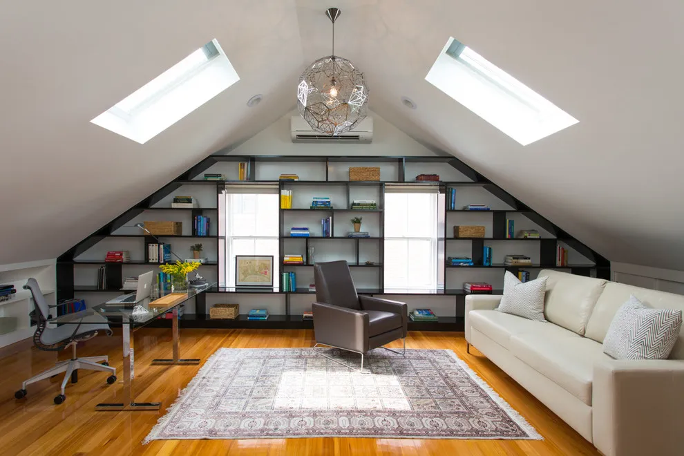 Open shelving follows the sloped end wall beside a desk and small sitting area