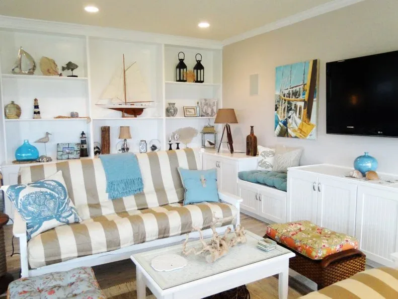 Broad-striped sofa in a coastal room with white built-in shelves, a model sailboat and blue accessories.