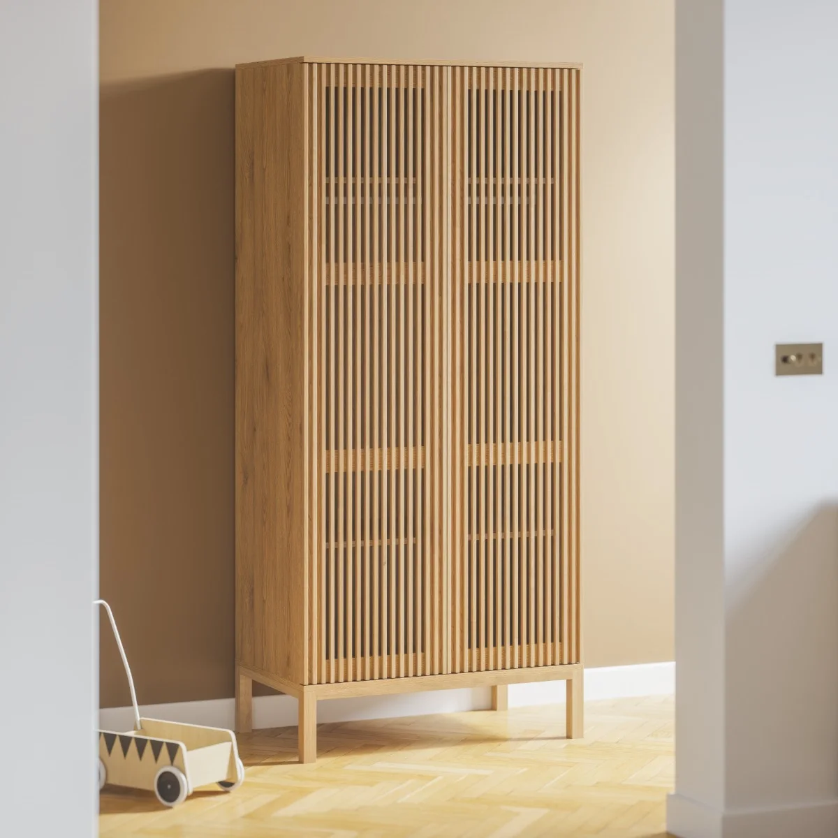 A tall wooden wardrobe with closely spaced vertical slats stands against a warm neutral wall