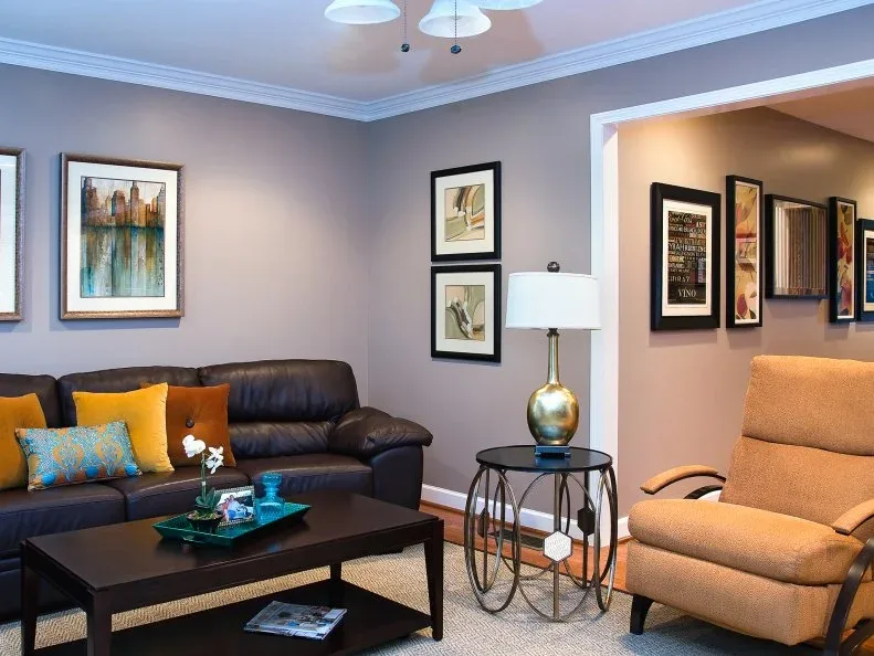 A dark brown leather sofa with yellow cushions sits beside a yellow armchair, gray walls and a dark coffee table
