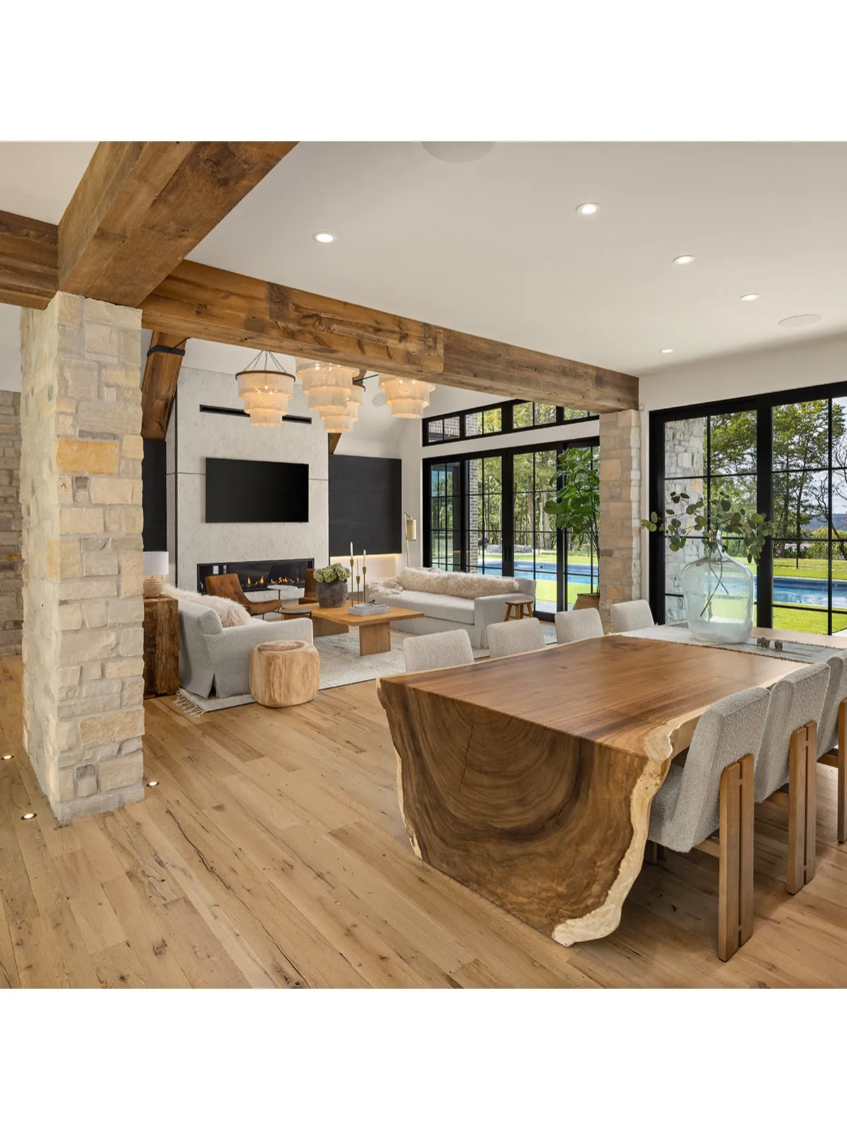 A timber table stands beneath broad exposed beams beside pale seating.