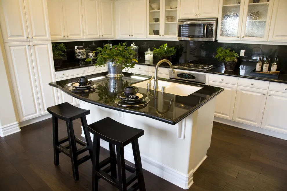 White cabinets sit beneath deep counters and a dark backsplash around a small island