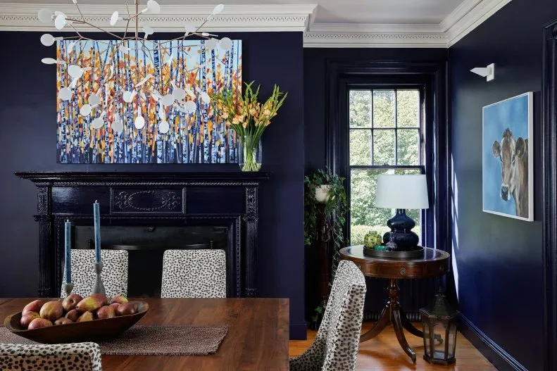 Shallow bowl of mixed fruit on a short textured runner across a wood table in a navy dining room