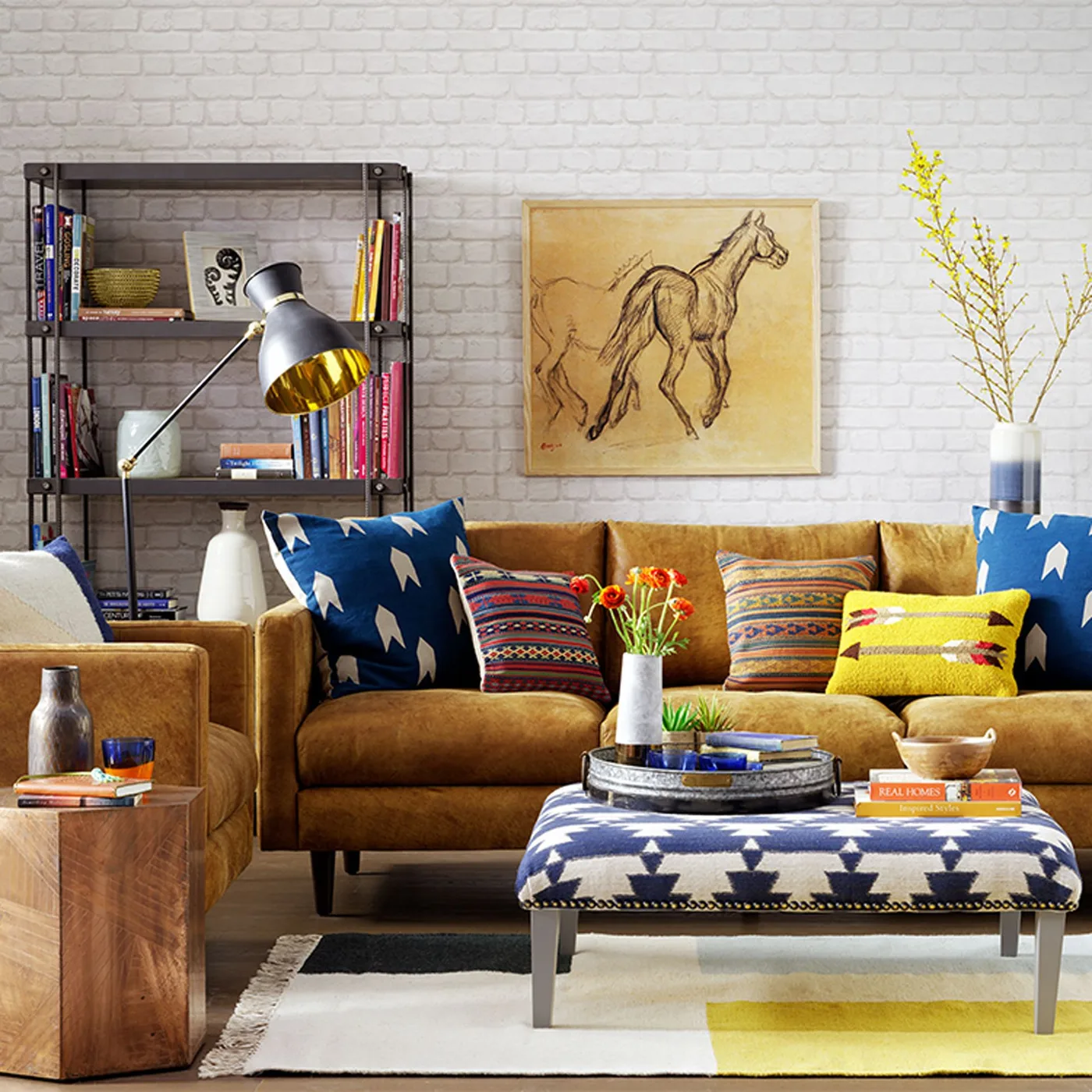 Ochre couch with blue pillows bearing pale arrow motifs, multicolored striped pillows and a yellow accent pillow.