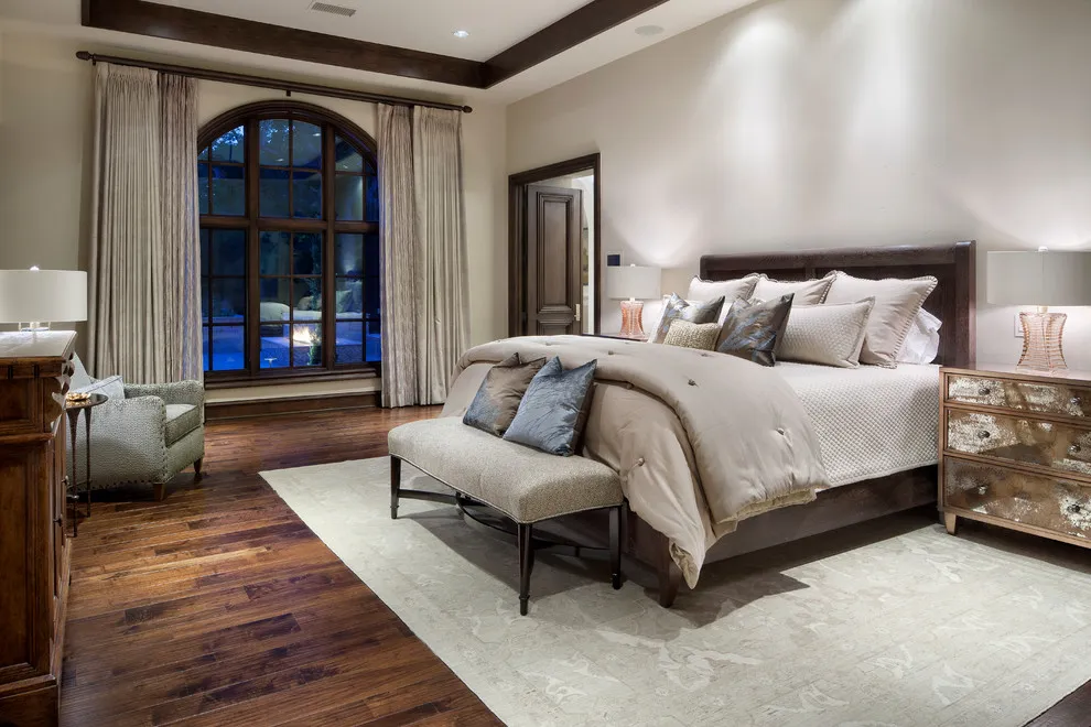 A dark timber bed with pale bedding and a light bench sits above varied brown floorboards