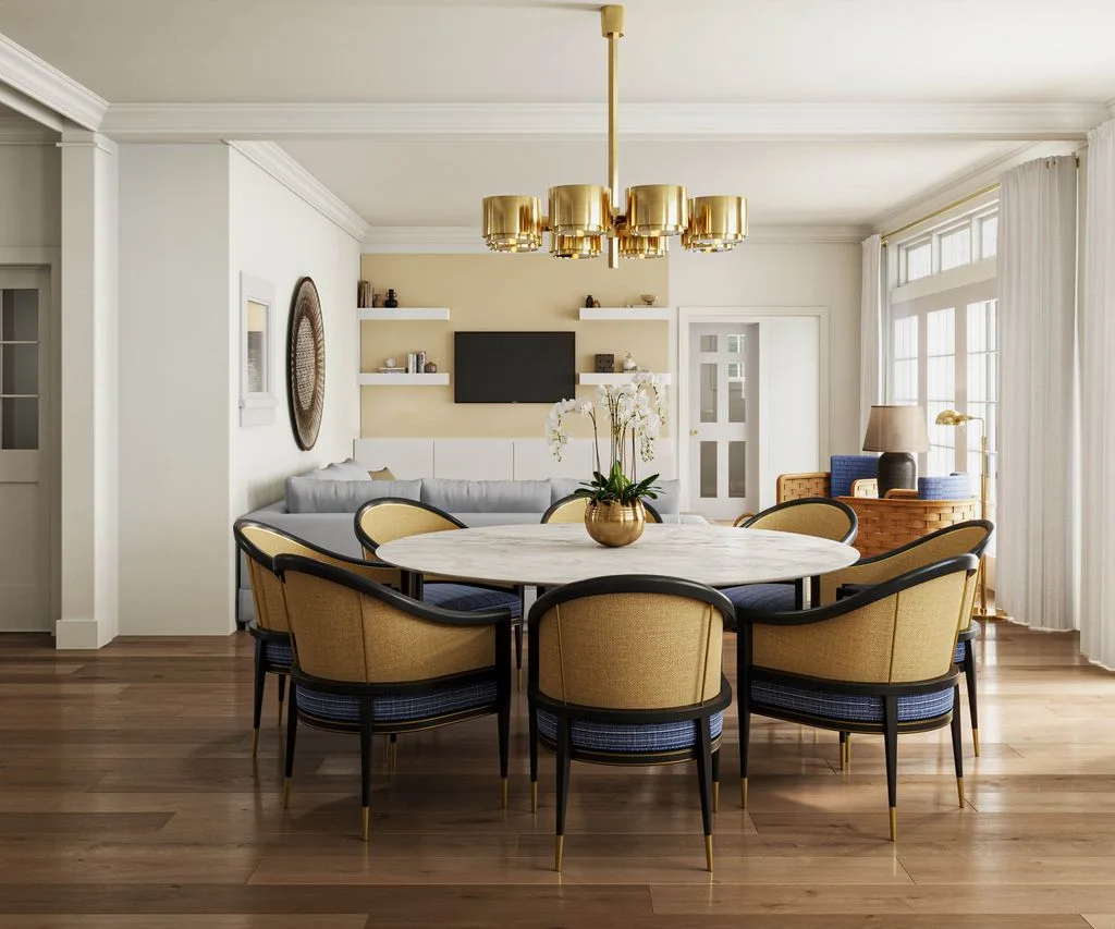 Rounded yellow dining chairs surround a pale round table beneath a gold-toned multi-shade light in an open room with a sofa and wall shelves