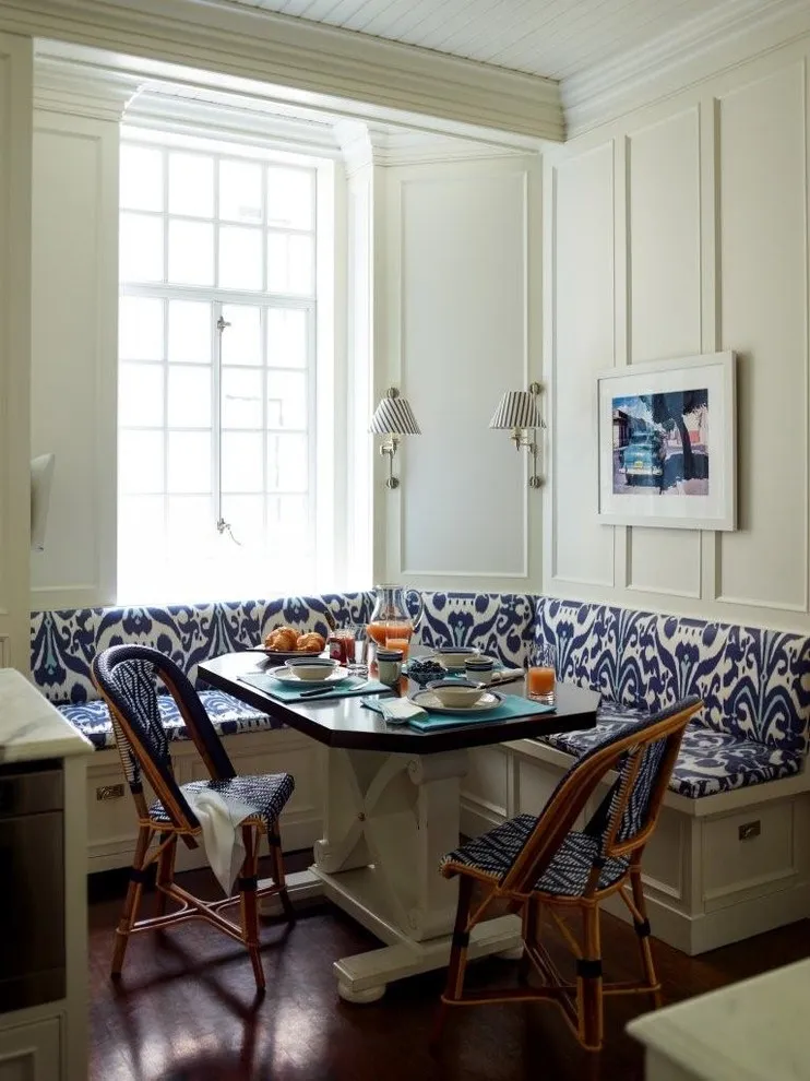 A patterned corner banquette wraps a small table beside a window