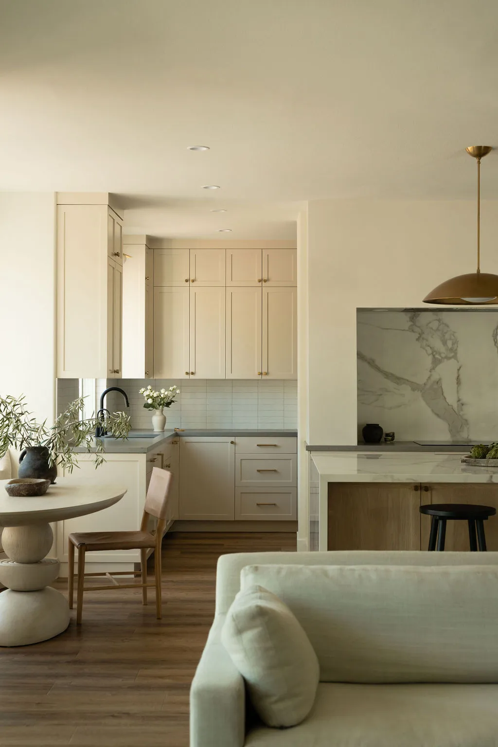 Pale beige cabinets sit beyond a softly colored sofa in an open room