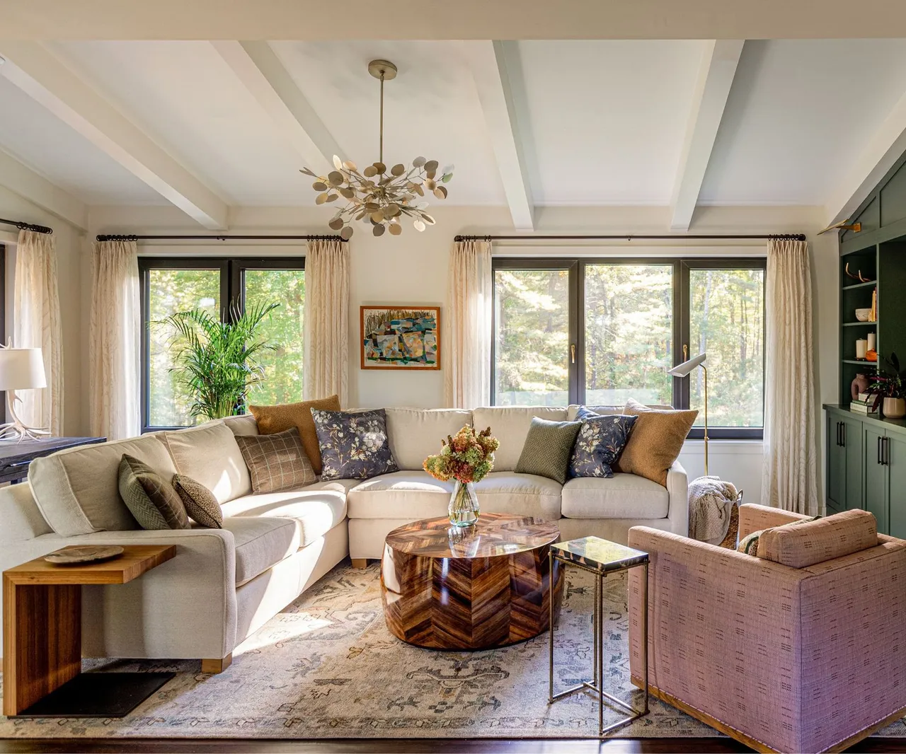 Pale sofas and chairs surround a low central table beside broad windows.