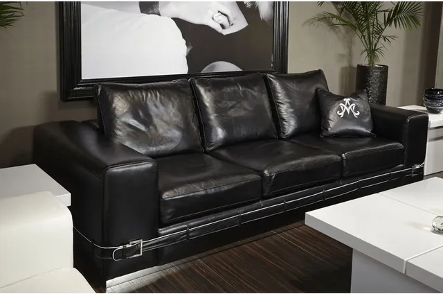 A black leather sofa sits below graphic artwork beside a pale low table.