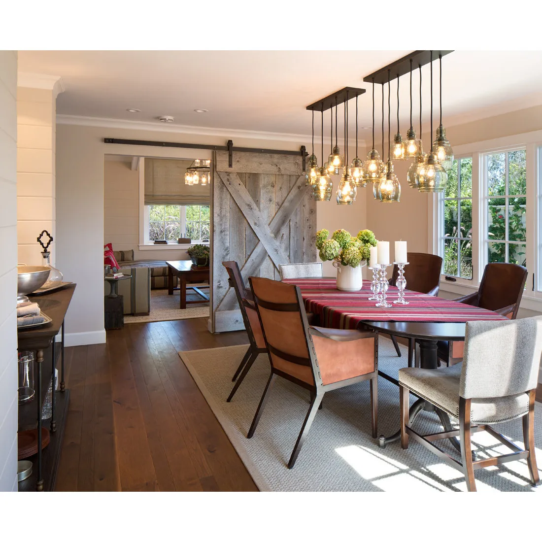 Dining room with brown chairs and glass pendants beside a sliding door opening to a desk and bench