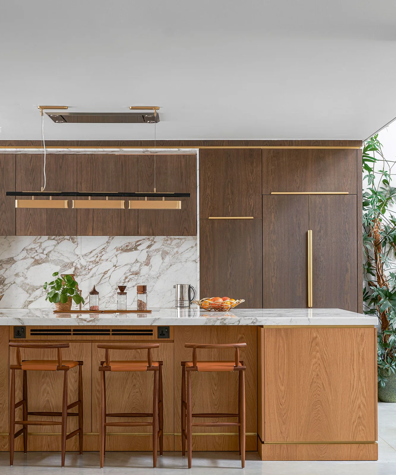 Dark wooden kitchen cabinets and a lighter wooden island sit beside a pale veined backsplash