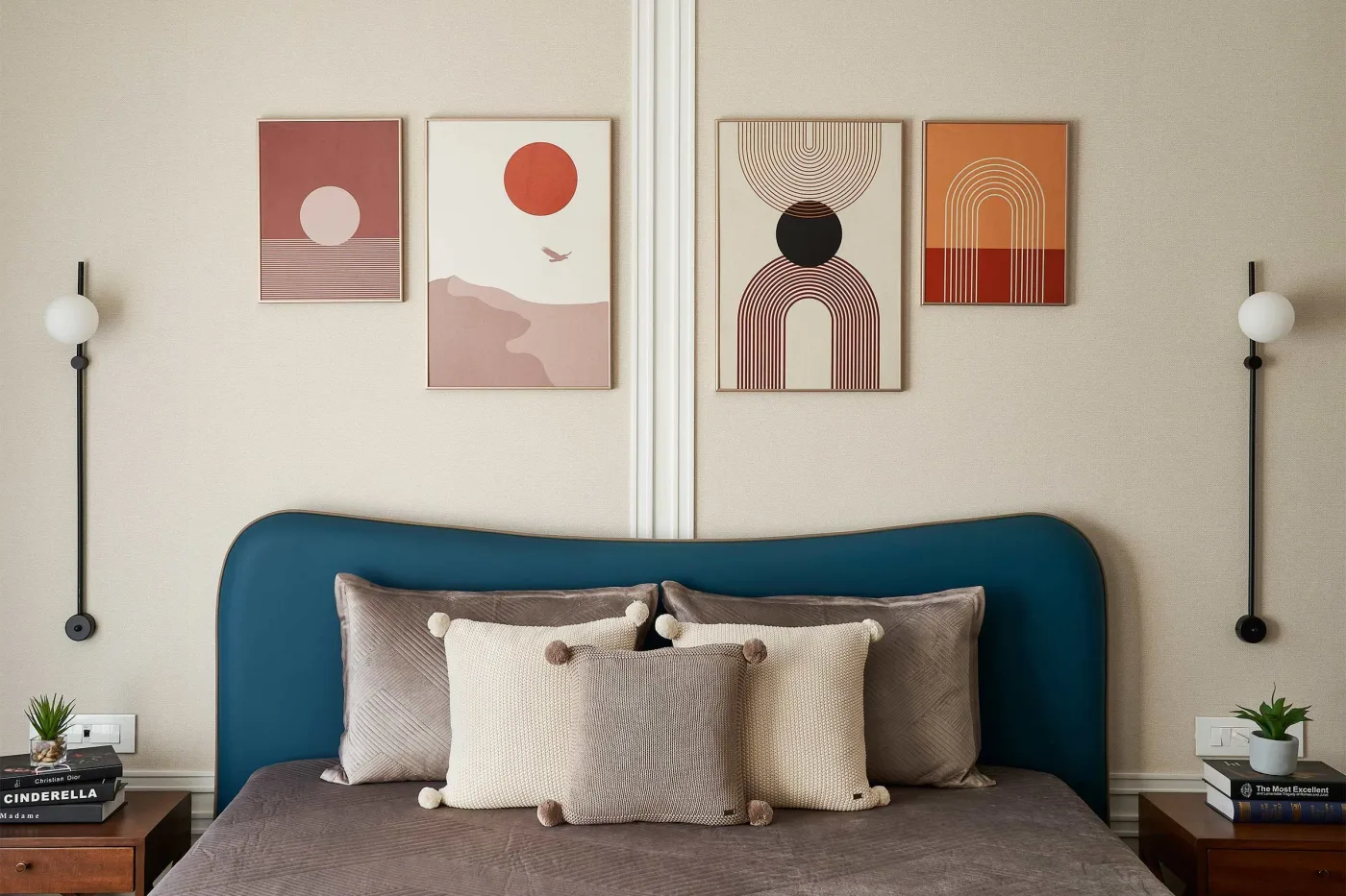 Teal curved headboard beneath four warm-toned abstract prints with circular forms and paired globe wall lights.