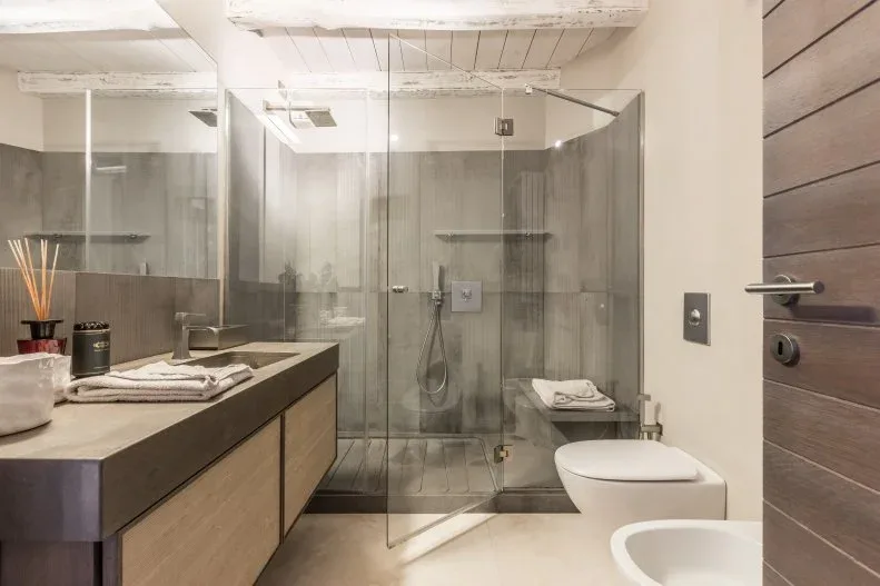 Taupe-toned bathroom with wood vanity fronts, a glass shower enclosure and a broad wood door