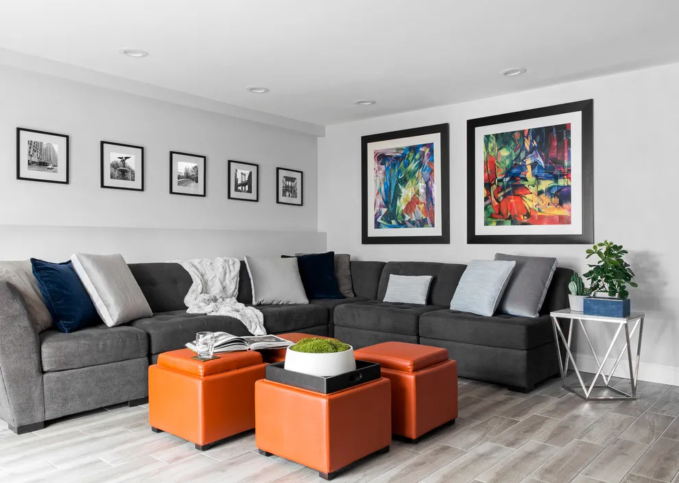 A row of smaller monochrome pictures hangs above a gray sectional beside larger colorful artwork
