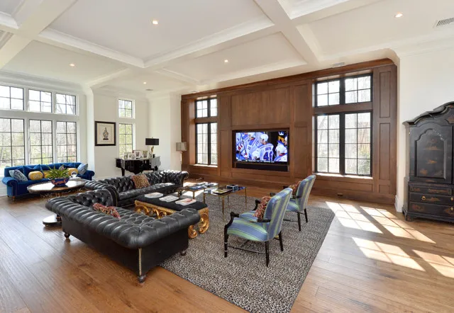 A black tufted sectional faces a timber television wall beside a blue sofa and blue-striped chairs.