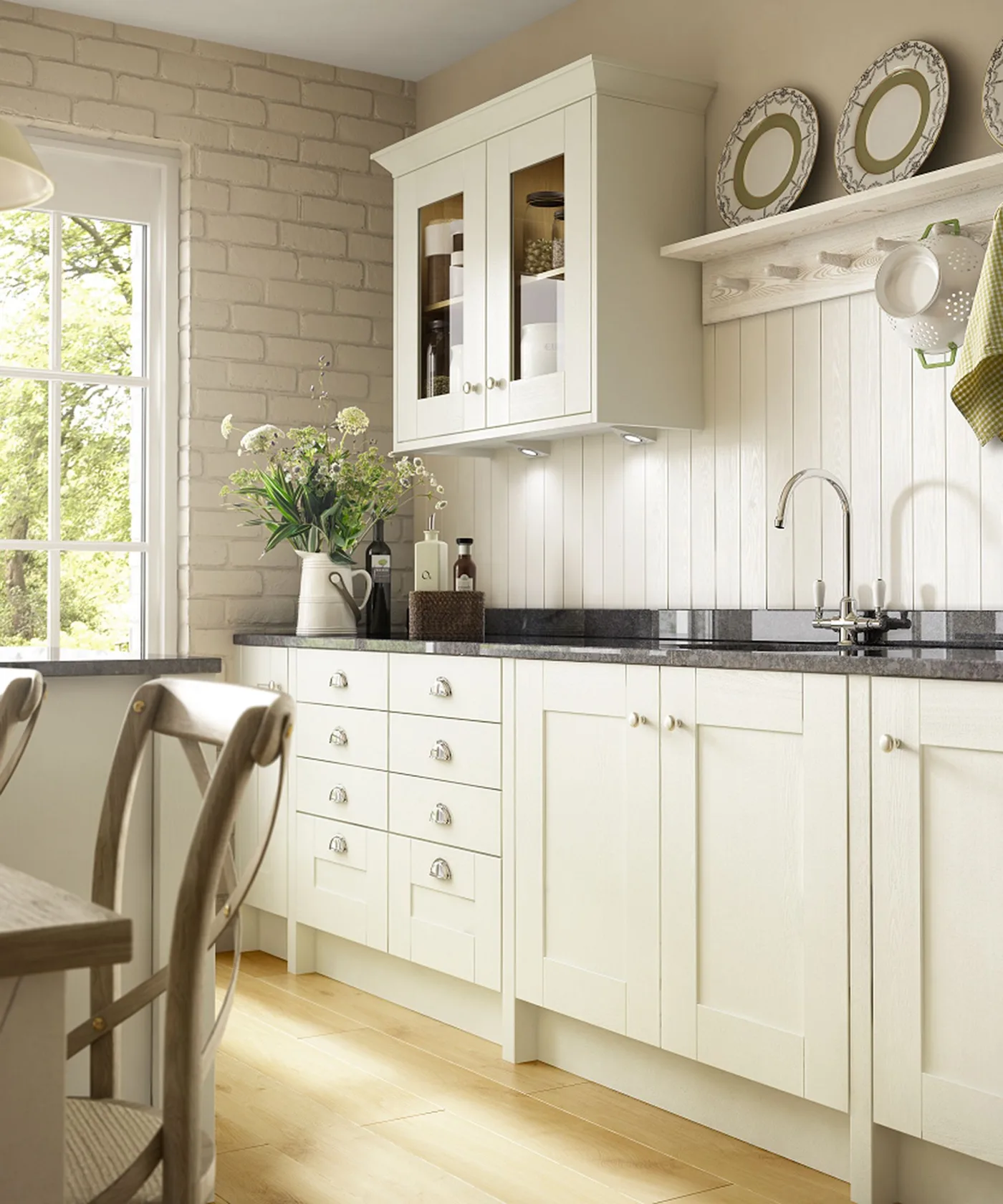 Pale framed kitchen cabinets beneath a dark worktop, white glazed wall cupboard and a paneled wall with plate shelf.