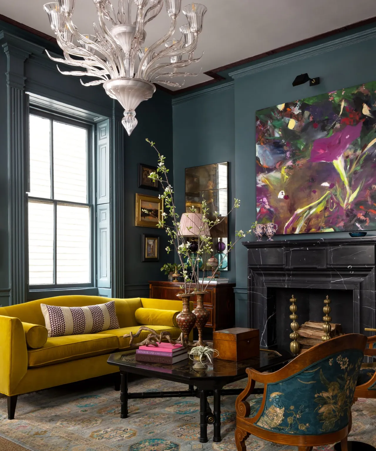 A bright yellow sofa sits beneath deep blue walls and colorful artwork.