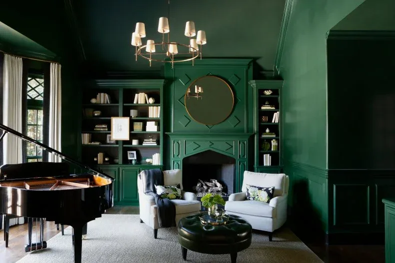 Deep green study with matching fireplace wall, ceiling and bookcases, pale chairs and black piano