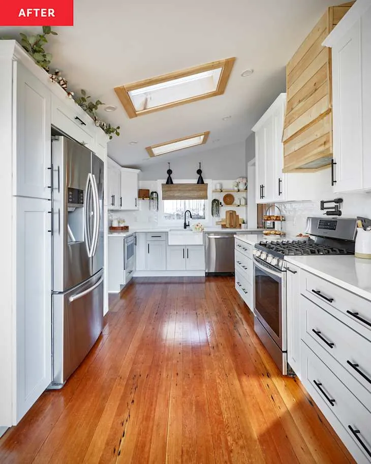 Bright white farmhouse kitchen with restored timber flooring, wood-trim skylights and simple open shelves