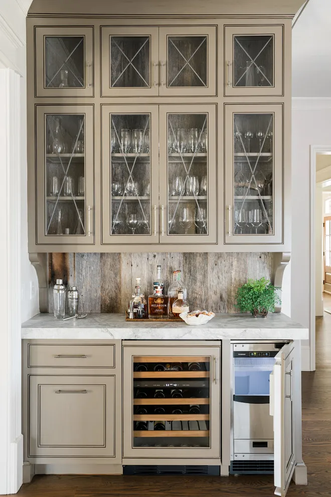 A taupe beverage cabinet has patterned glass doors, a light counter, and an under-counter wine cooler