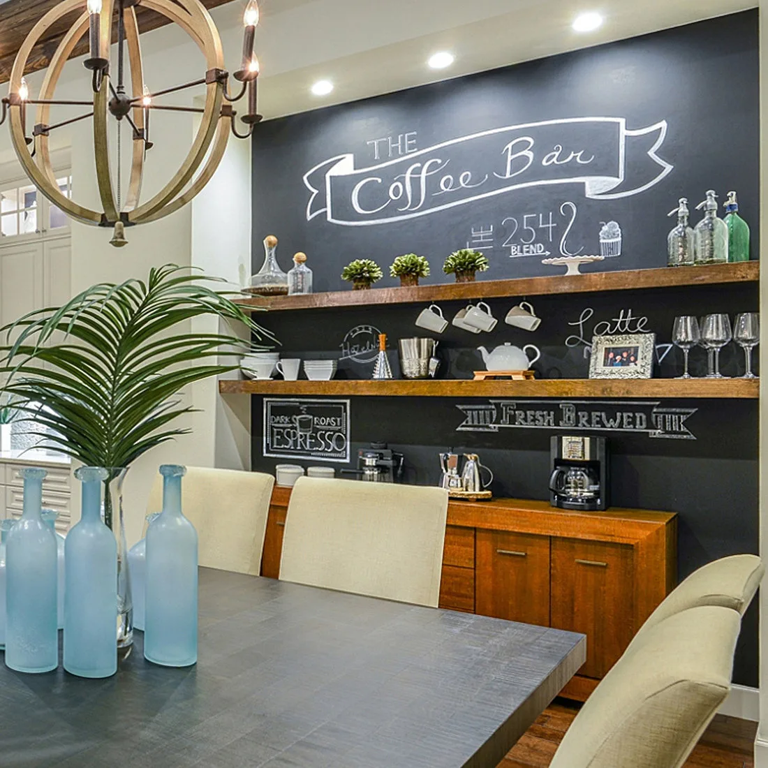 Two wood shelves with cups and glassware on a dark chalkboard-style wall above a dining coffee cabinet