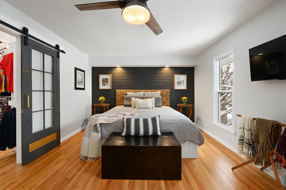 A dark painted wall frames a bed between pale side walls in a long bedroom