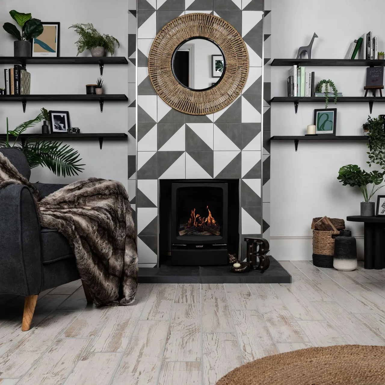 Dark bracketed alcove shelves beside geometric fireplace wall with round woven mirror and plants