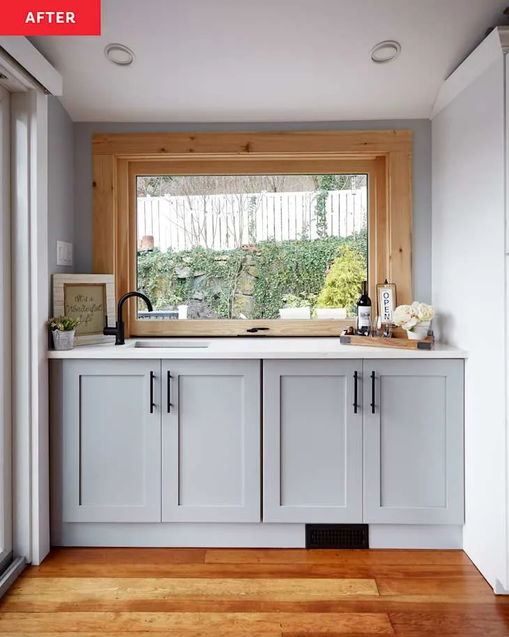 Light-filled farmhouse kitchen with timber-framed picture window, slim sink run and natural wooden flooring