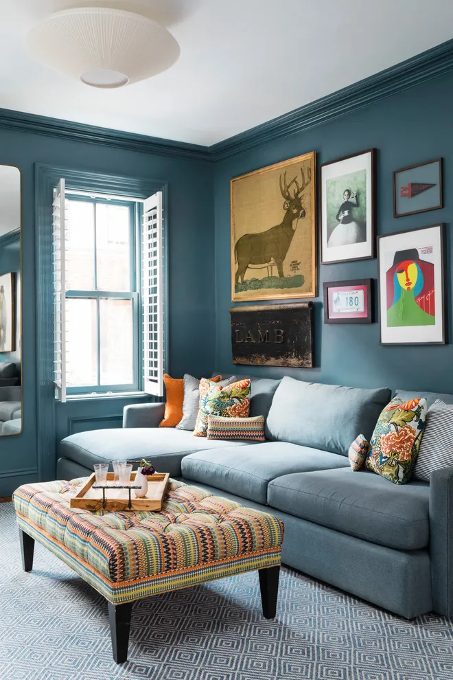Mixed artwork hangs above a gray sofa against deep blue walls