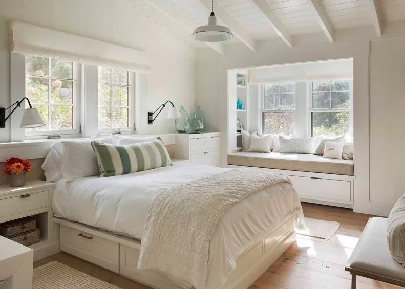 White country bedroom with storage bed, built-in bedside drawers, striped cushion and window seat