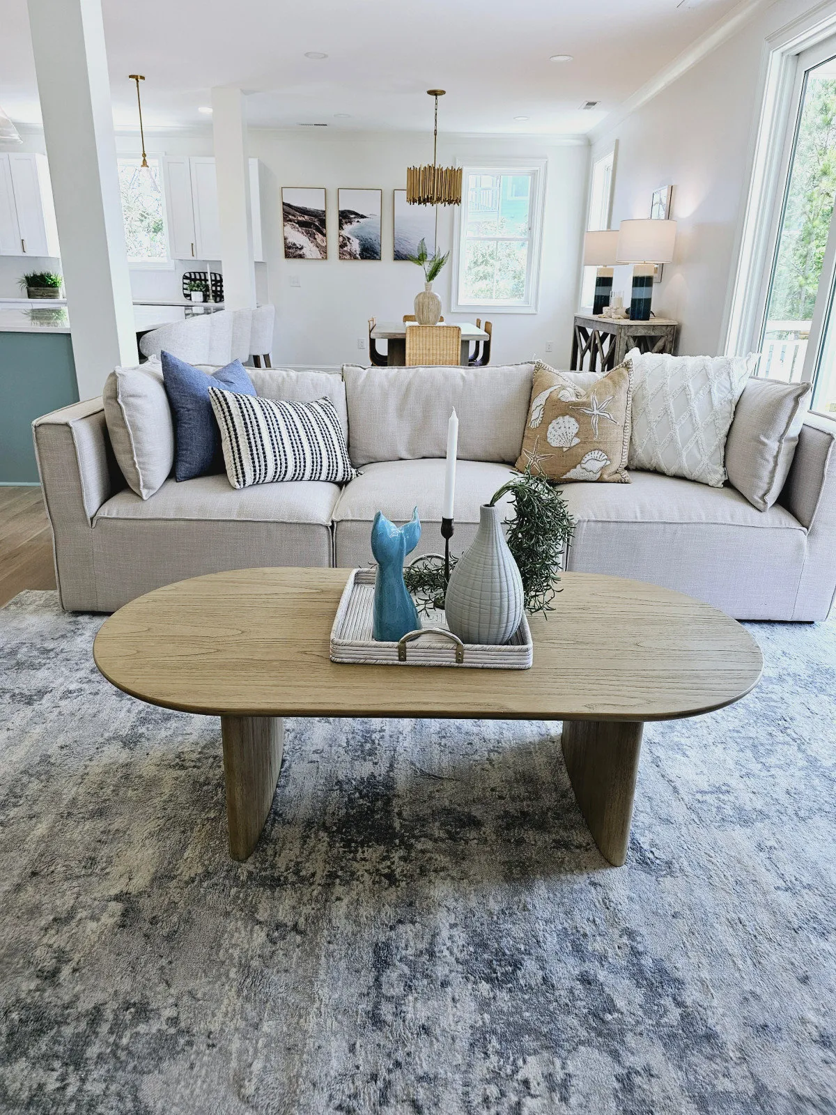 A pale sofa sits behind a rounded timber table with blue-and-white pillows.
