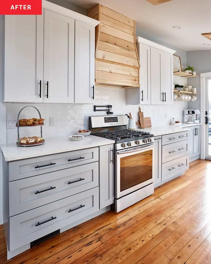 Updated white Shaker cabinets around steel range with a timber-clad vent hood and timber flooring