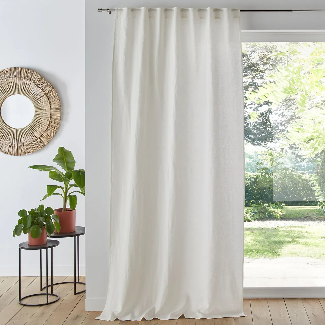 Light curtains hang beside a broad window, small plant and simple woven wall detail.