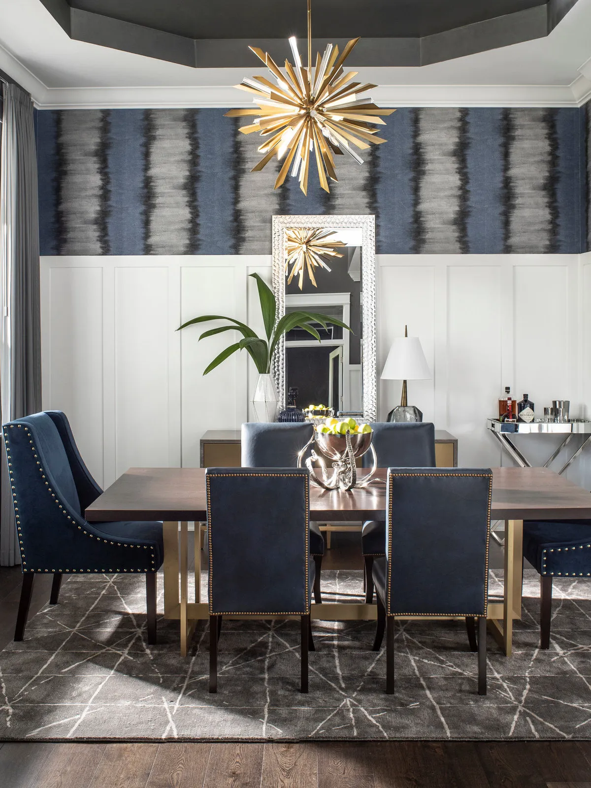 Dark vertical wallpaper bands rise above bright white paneling behind a dining table.