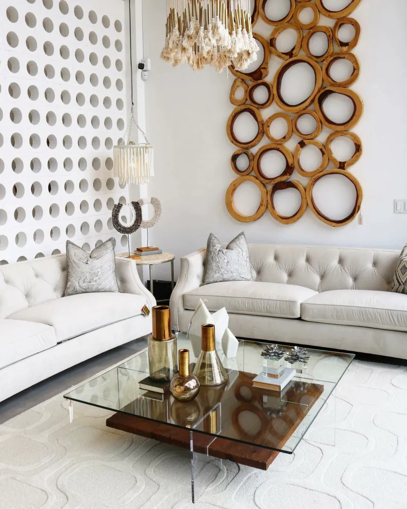 Warm-toned circular wall decoration above pale sofas beside a patterned wall