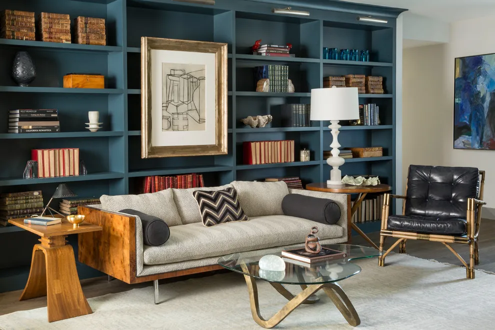 A large framed print sits within dark shelving above a pale sofa