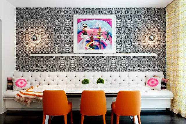 Small black-and-white pattern covers the wall above a white banquette and orange chairs.