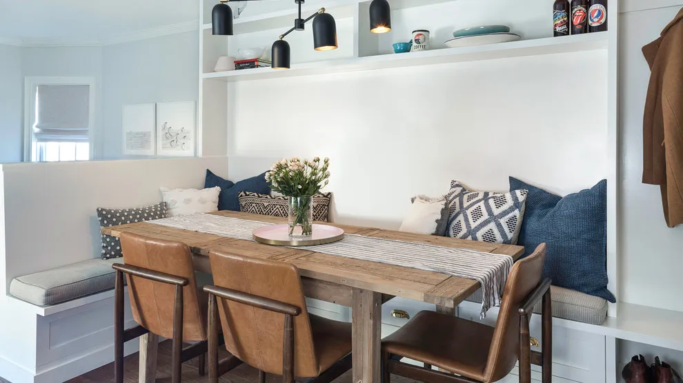 A timber table stands beside a built-in bench and loose chairs
