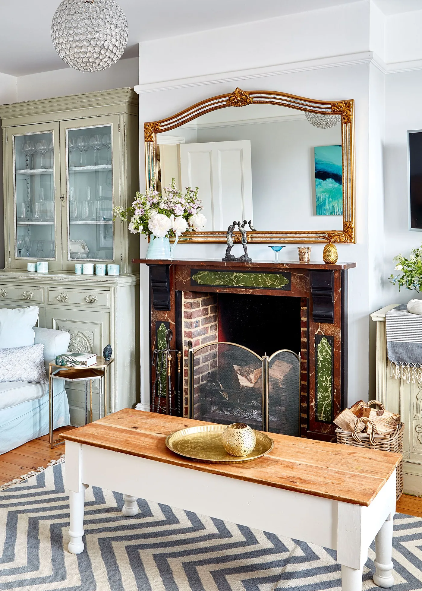 Traditional dark wood fireplace with green panels, curved mesh screen, tool stand and log basket