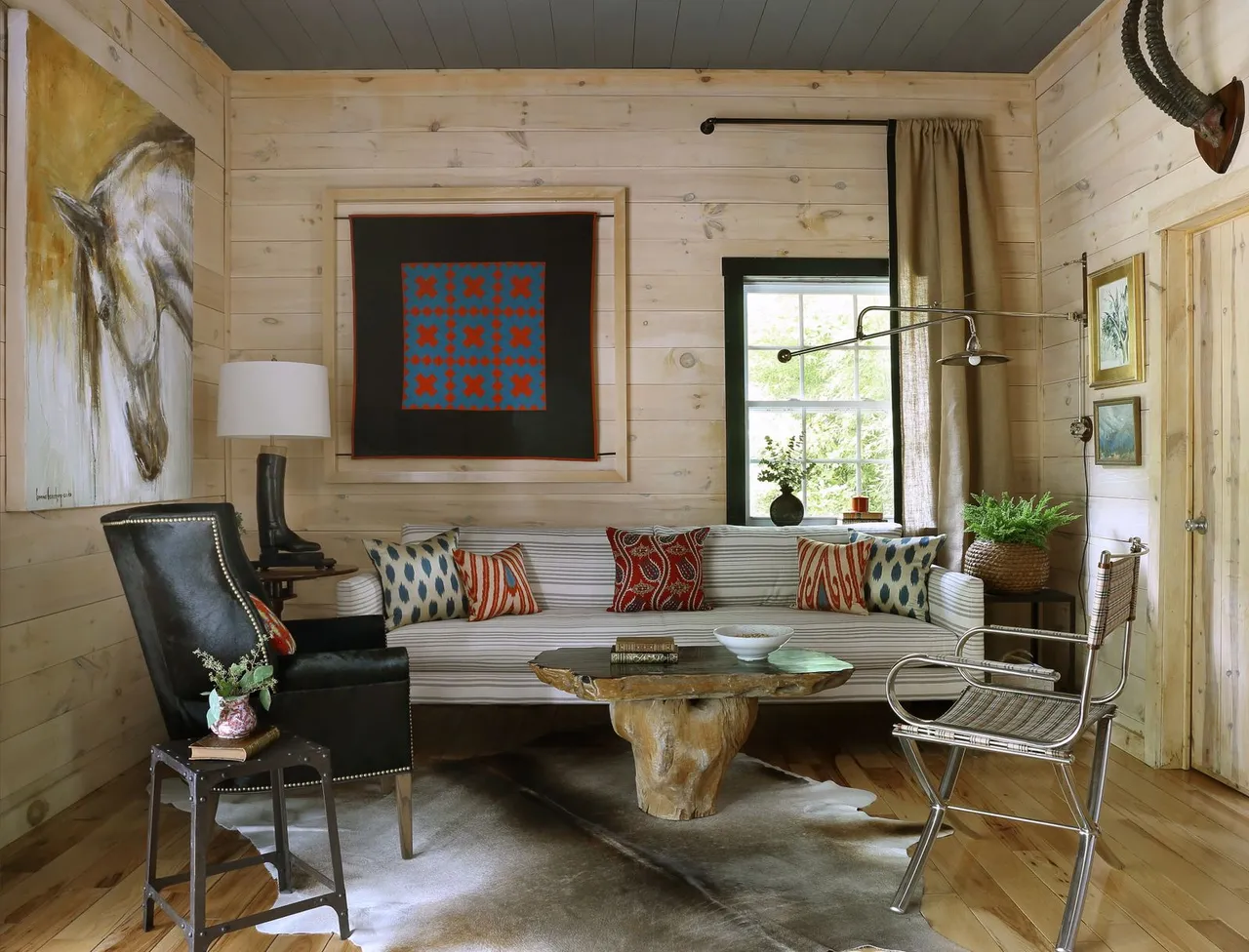 A pale built-in sofa sits behind an irregular timber table and two different chairs.