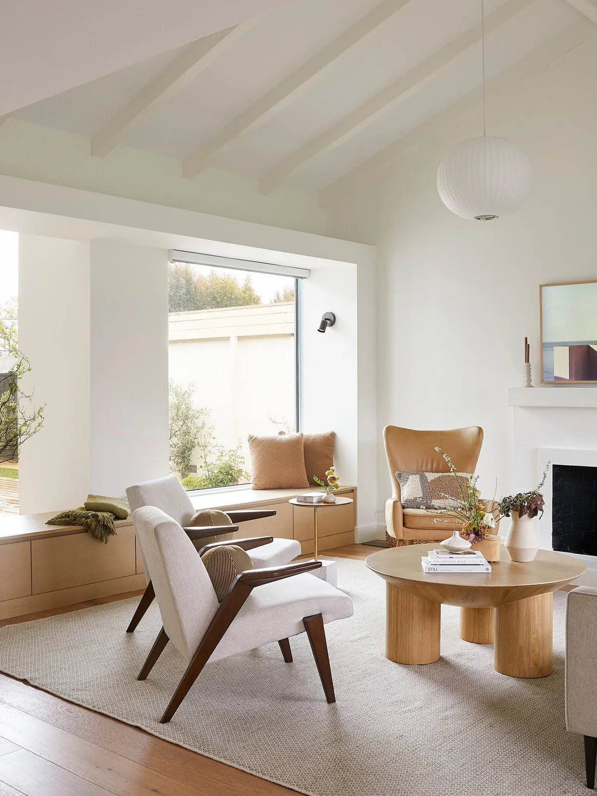 Two timber-framed chairs sit near a simple pale table beneath a bright ceiling.