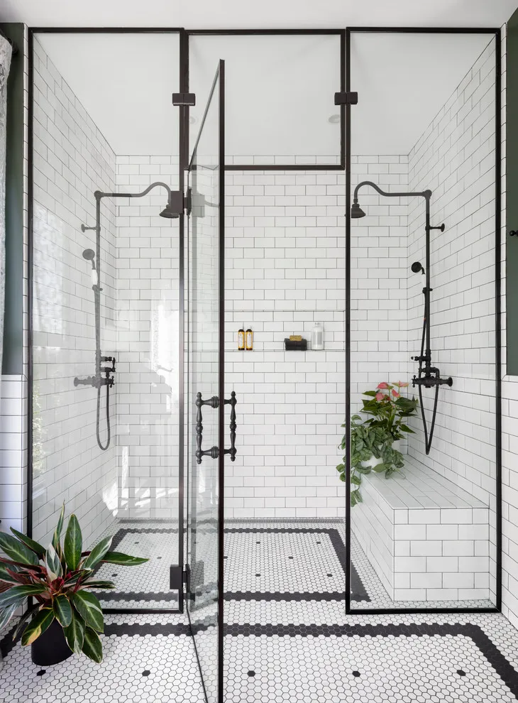 Small pale tiles with dark borders sit inside a black-framed shower