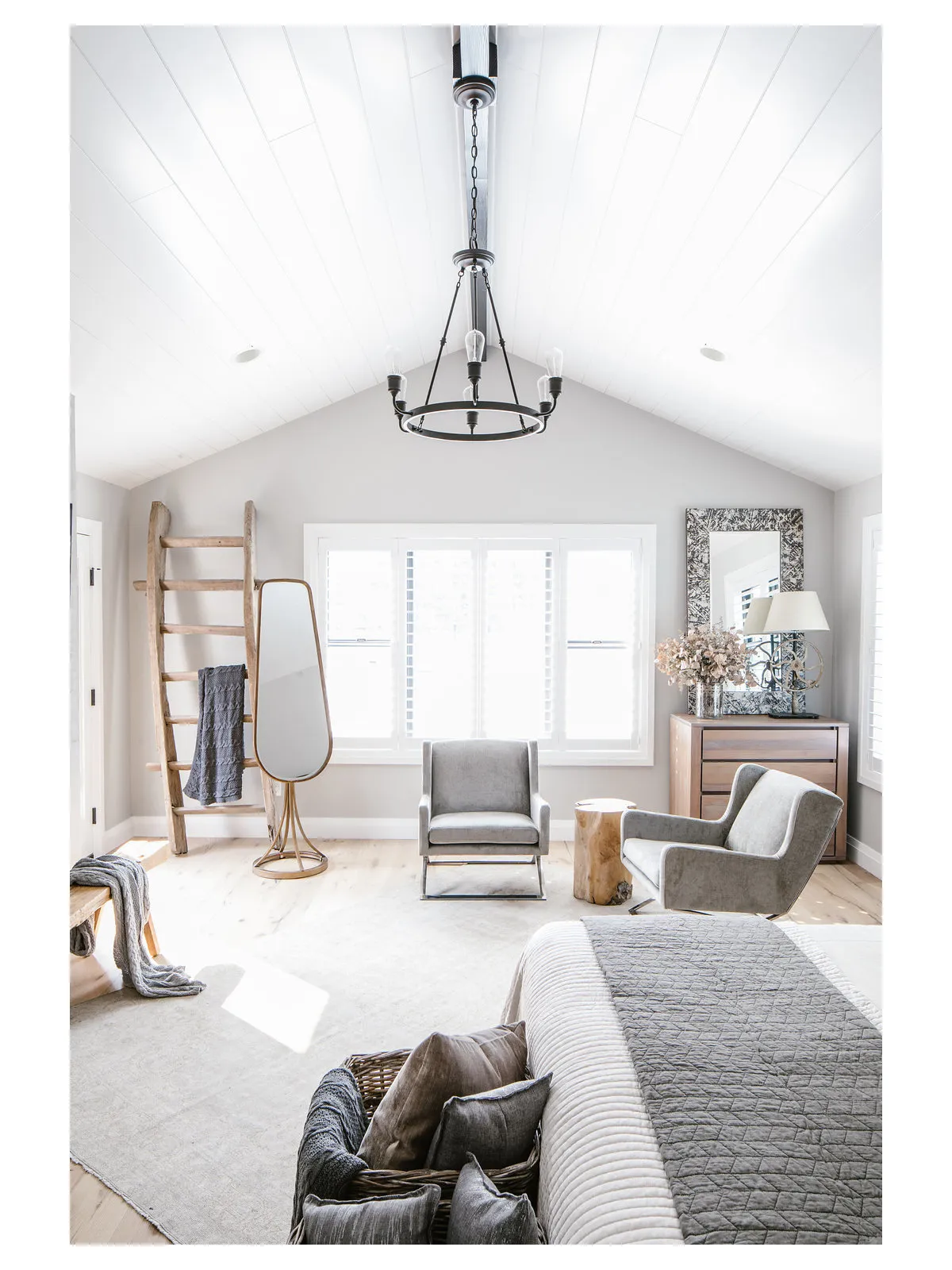 A bright vaulted bedroom places upholstered chairs near its broad window.