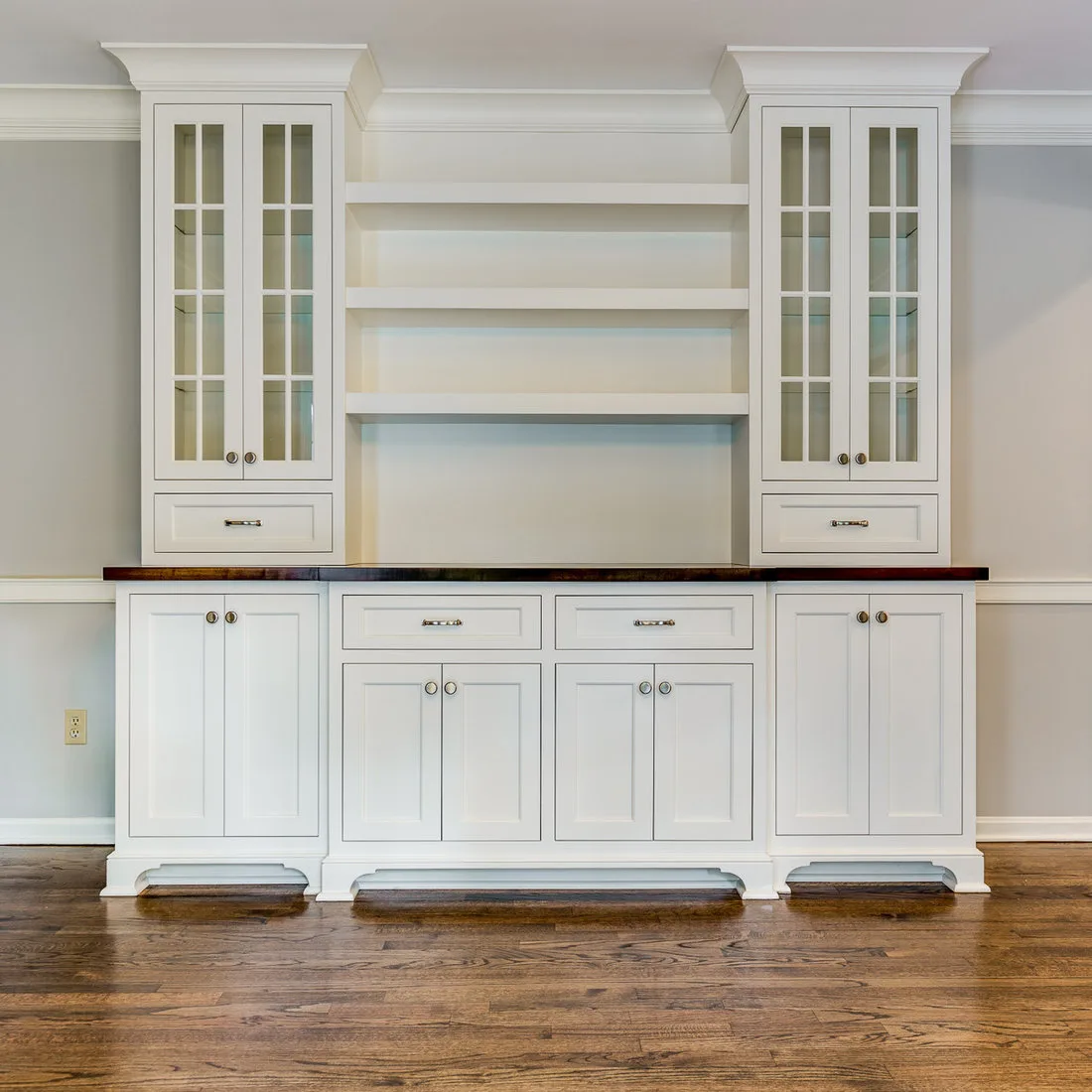 White serving cabinet with dark countertop, open central shelves and narrow glazed cupboards at the sides