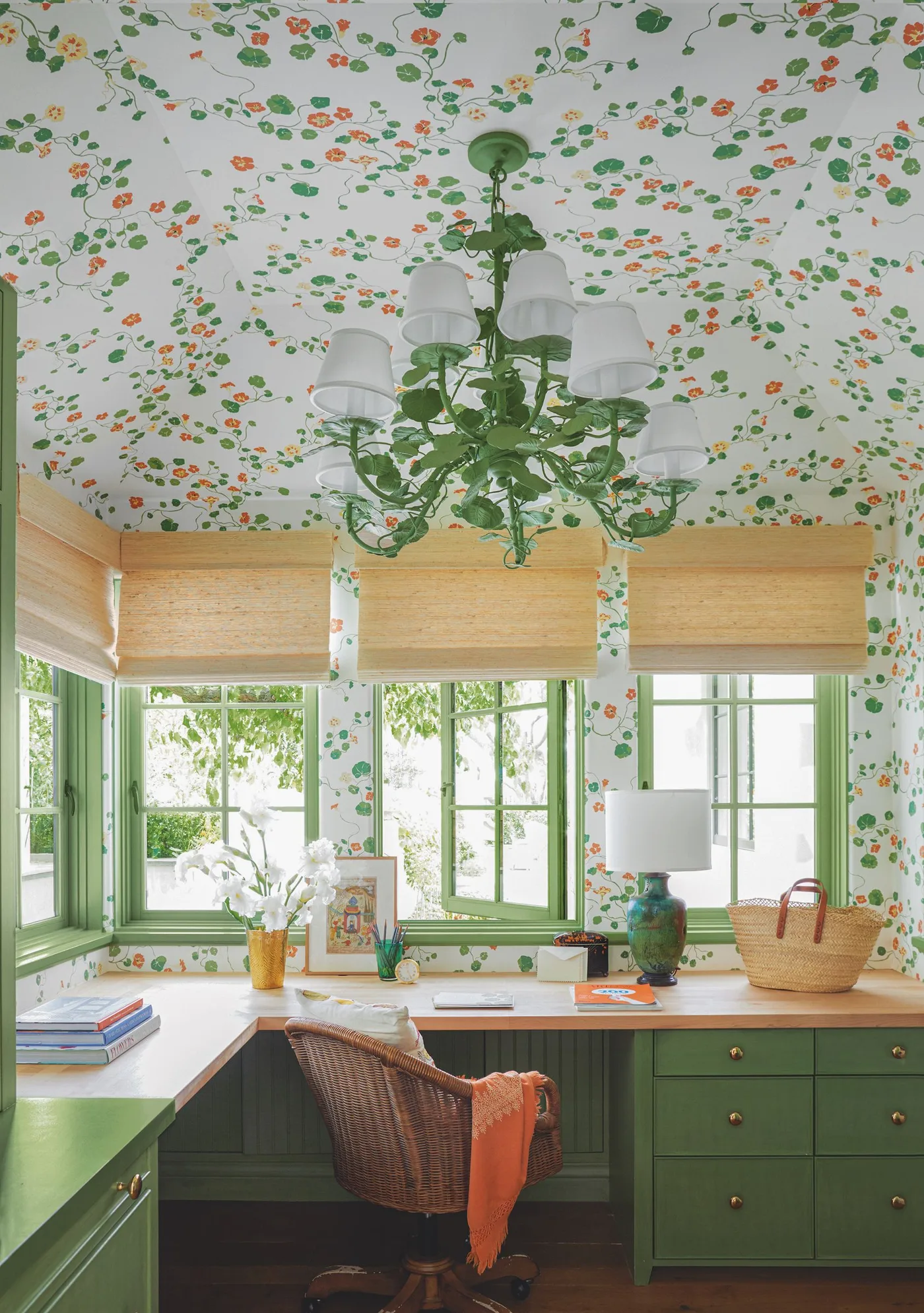 Country work corner with small green and orange floral wallpaper, green drawers and papered ceiling