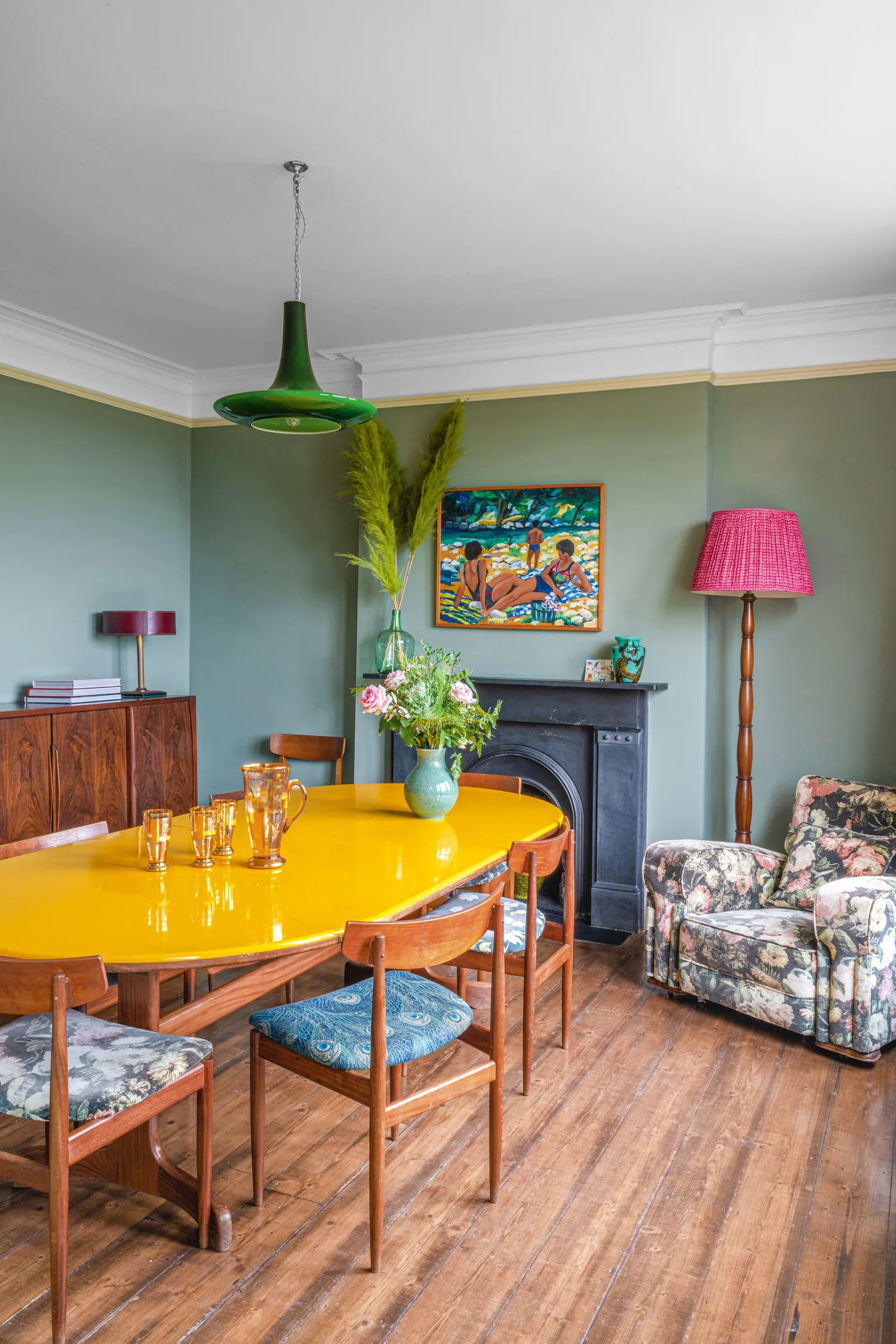 Green ceiling shade above a yellow oval table with a pink-shaded floor lamp and small sideboard lamp