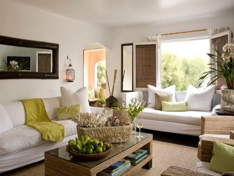 White sofas with green cushions and throw, a textured coffee table and a large dark-framed mirror.